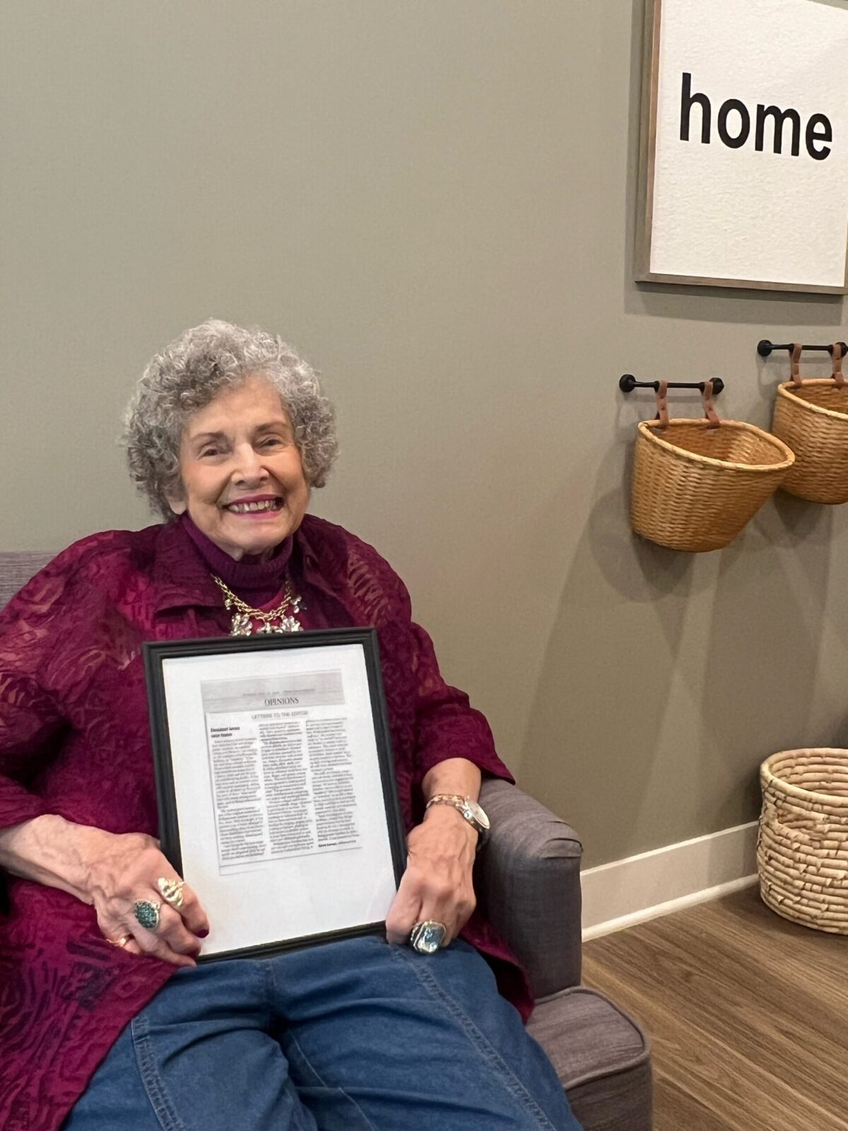 Smiling senior woman holding newspaper article